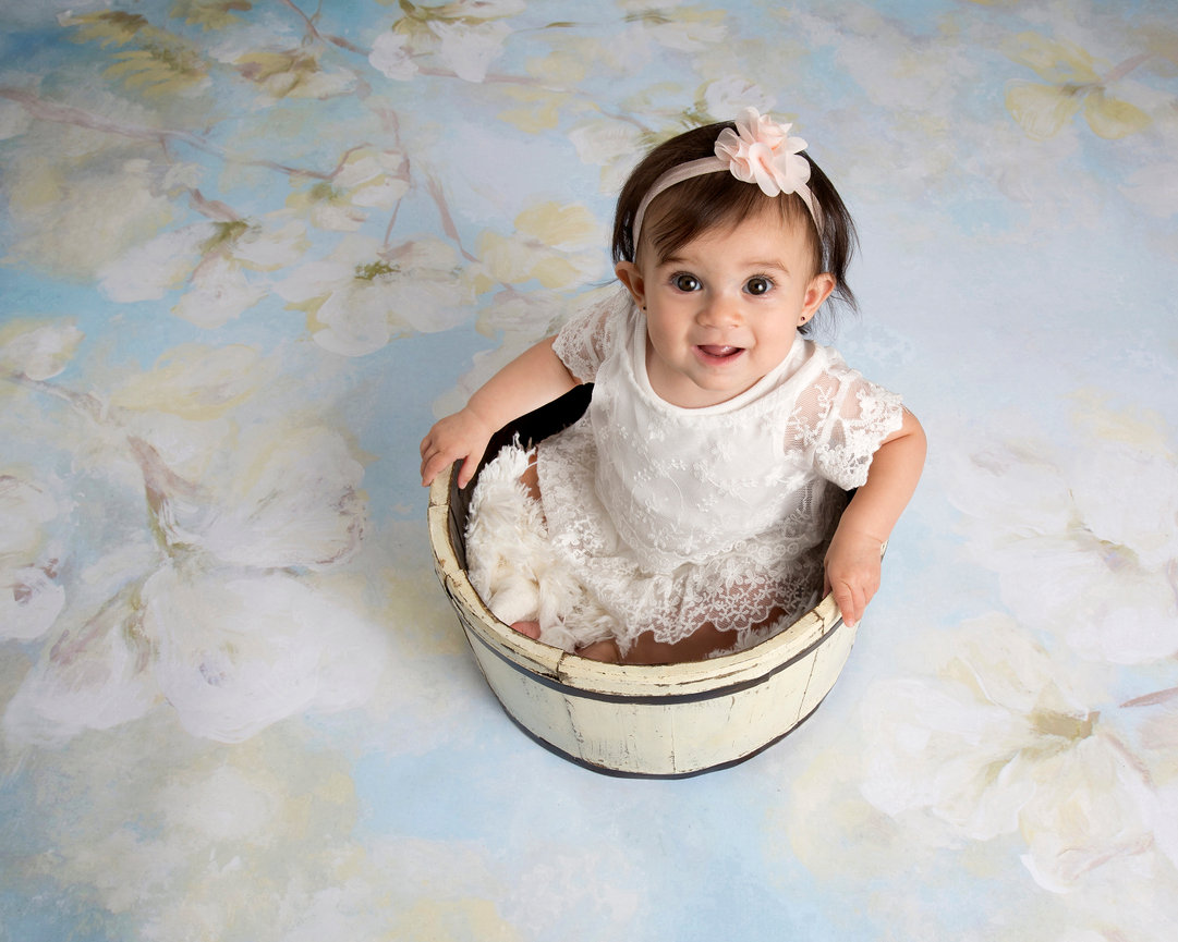 Young girl sitting in a basket wearing a white dress