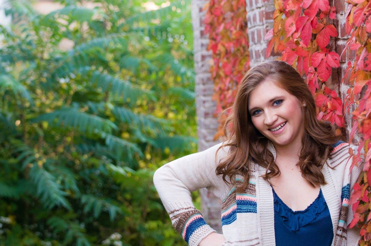 senior girl leaning against a wall with colorful ivy