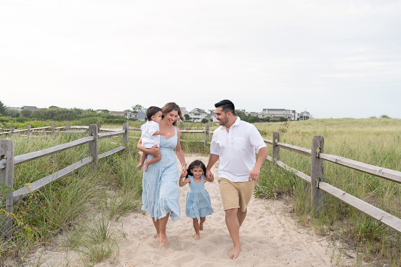 Lifestyle beach portrait featuring barefoot family in motion