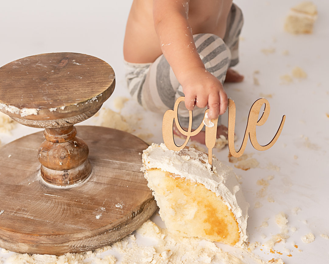 Close-up of baby hands and smashed cake on white floor during Shrewsbury birthday photoshoot