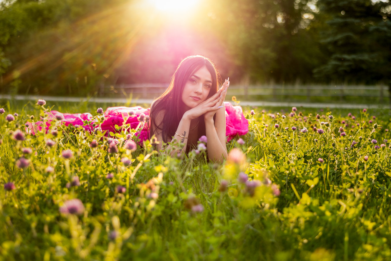 Woman in a field of wildflowers under a warm setting sun, with a soft focus and vibrant colors.
