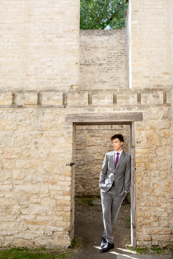 Young man in a gray suit standing in a stone doorway outdoors