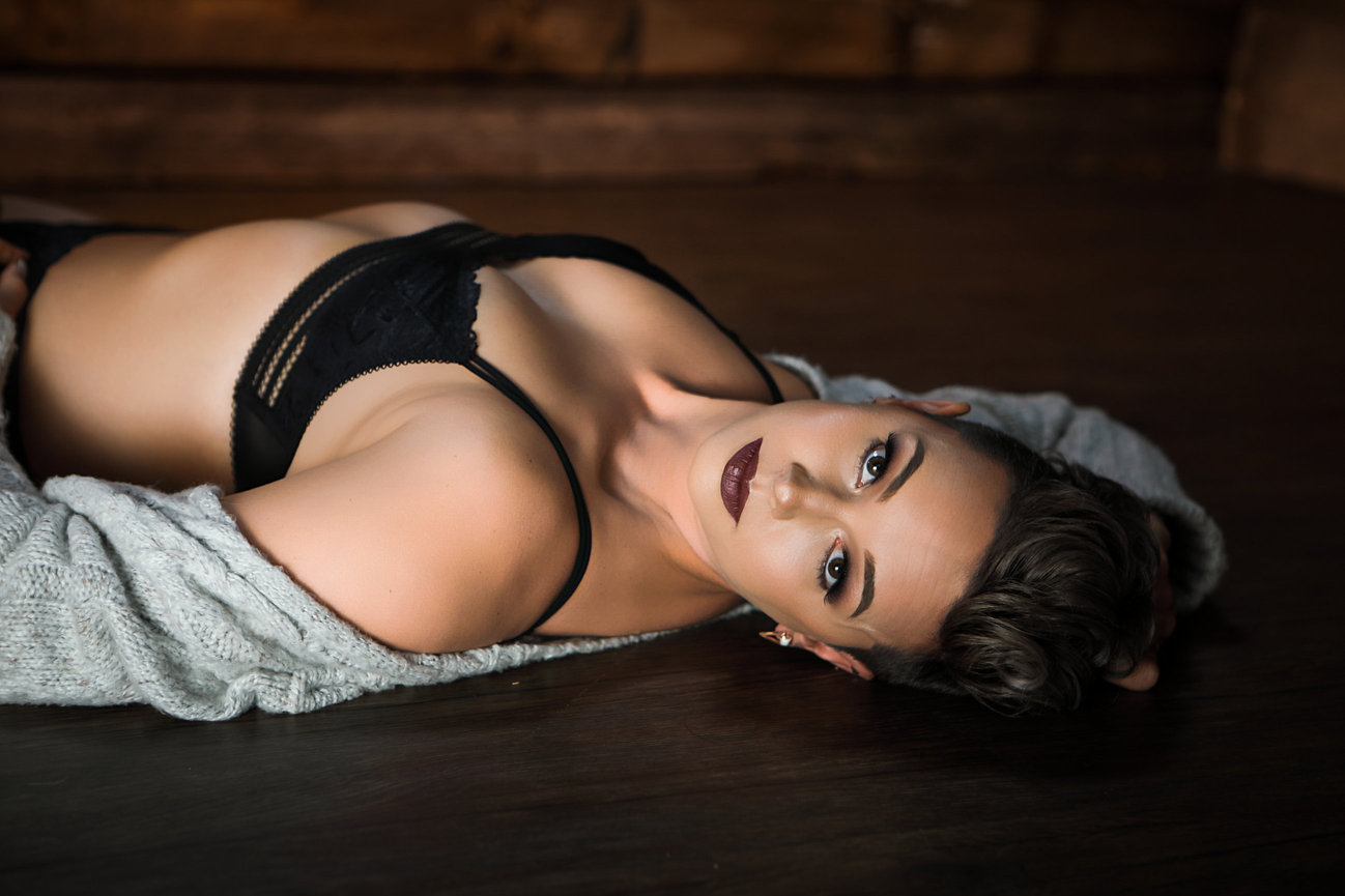 tasteful boudoir photo of a woman lying back with cardigan