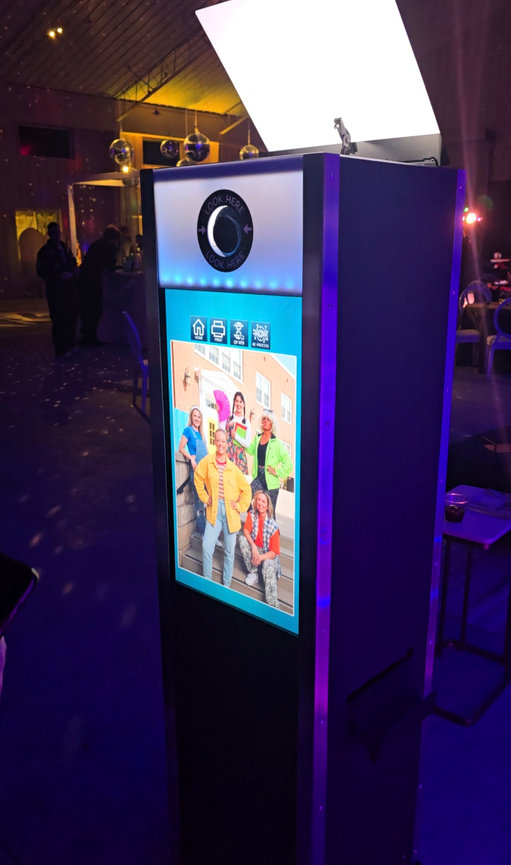 AI photo booth displaying a colorful stylized 90s high school themed group portrait on the vertical touchscreen.