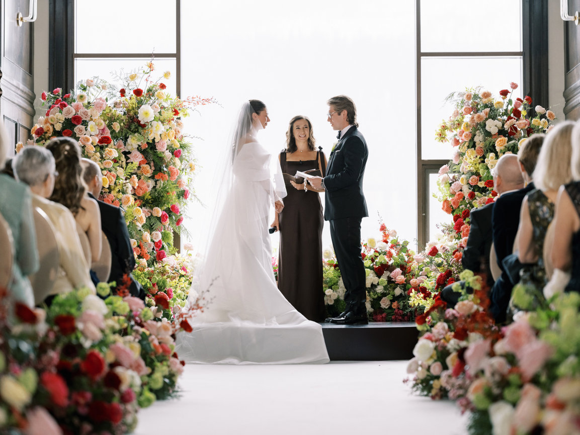 Bride and groom stand surrounded by vibrant floral stands and hedges at Fairmont Chateau lake louise wedding ceremony