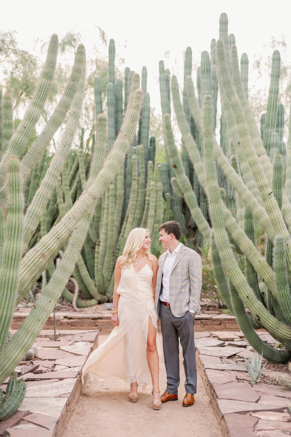 Engaged couple photographed by cactus at Desert Botanic in Phoenix, Arizona. Destination engagement photography by Heather Durham Photography.
