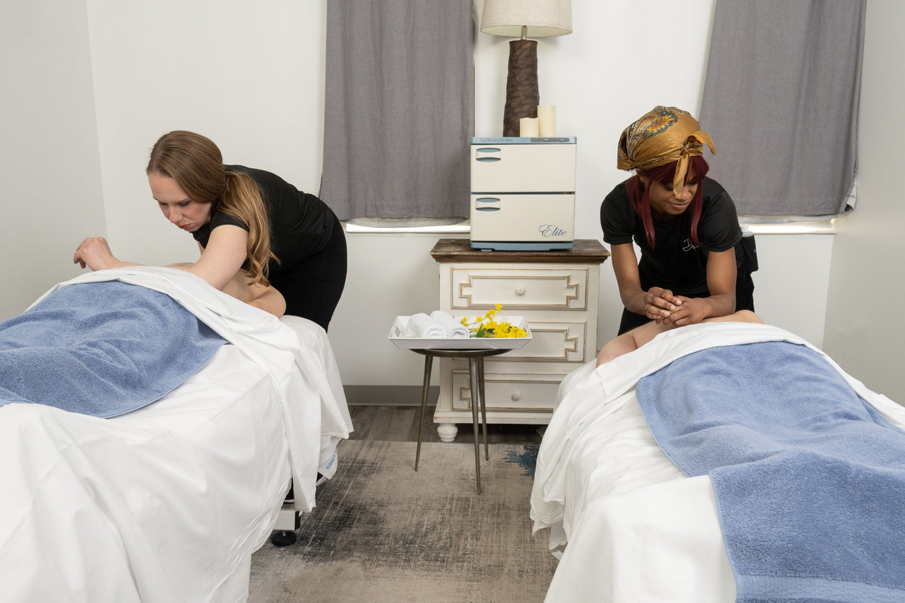 Two women doing a couples massage at a spa.