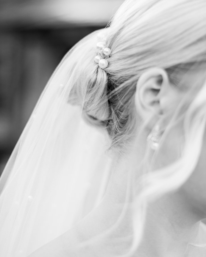 Black and white detail image of pearls in bride's updo. Wedding photography by Heather Durham.