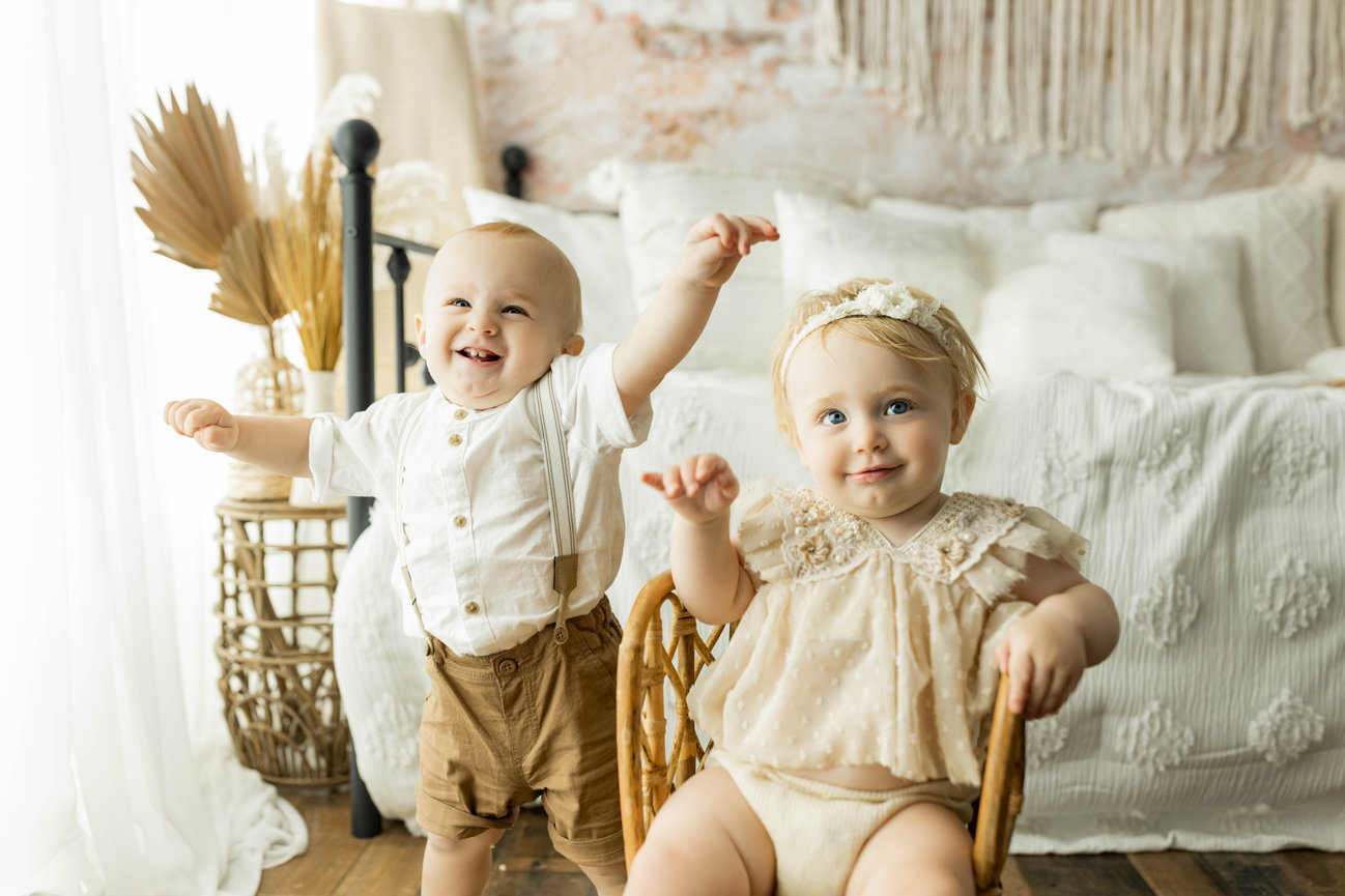 baby siblings in family photo shoot with bedroom backdrop
