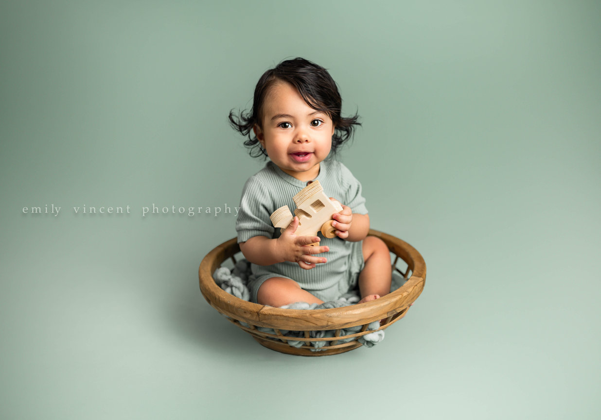 Sitting session portrait of baby in soft light green studio session backdrop