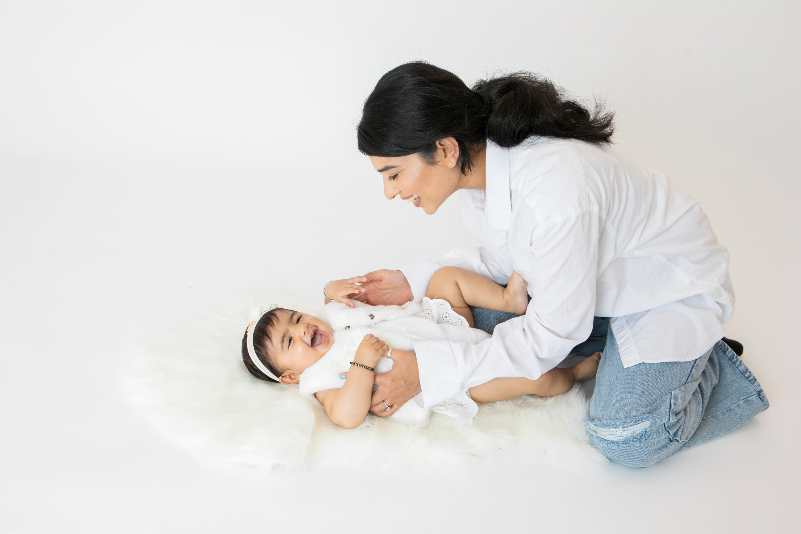 Parents smiling at their baby during a family milestone portrait
