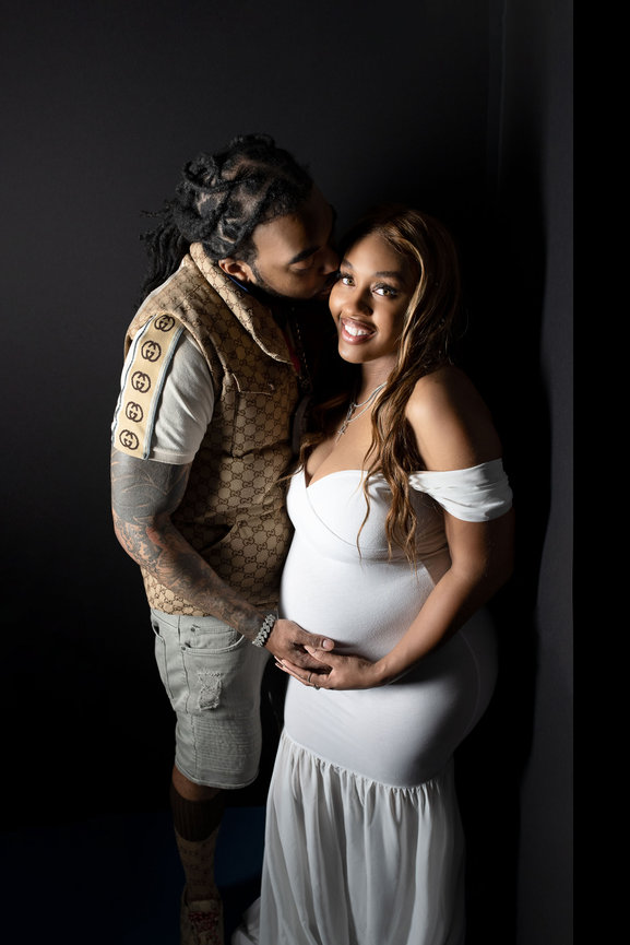 pregnant mom with dad touching her belly and giving her cheek a kiss