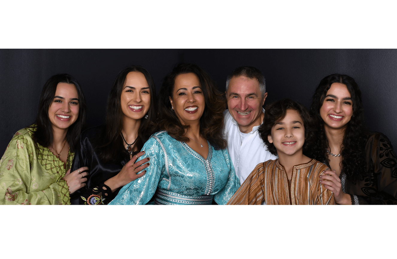A mother, father, three daughters and son wearing embellished native gowns.