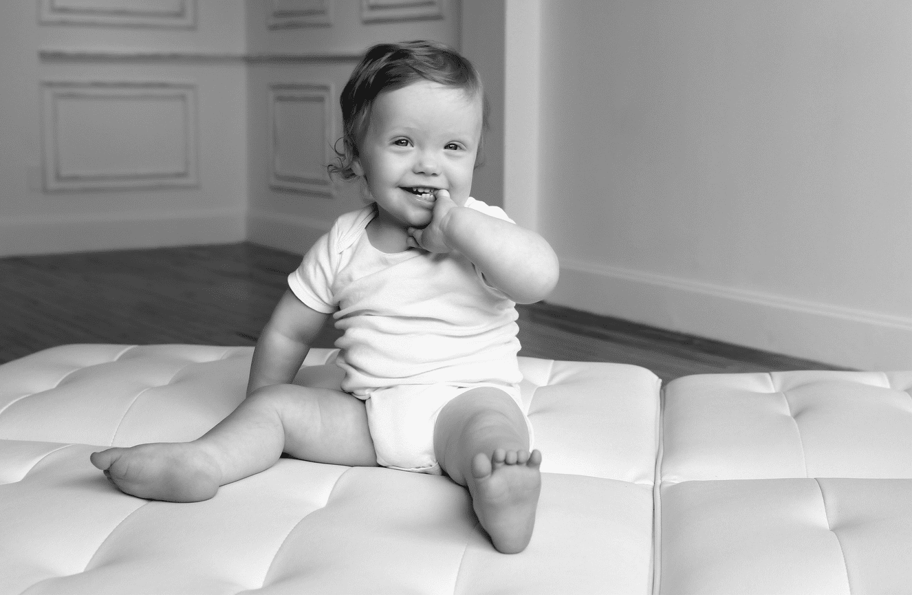 A happy toddler in a onesie showing off his bare toes during a family photo session at Kliks Photography.