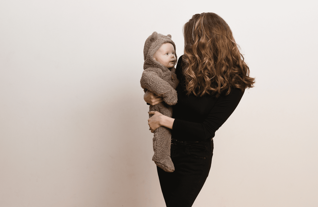 A mother and her infant wearing a little bear custom look lovingly at each other.