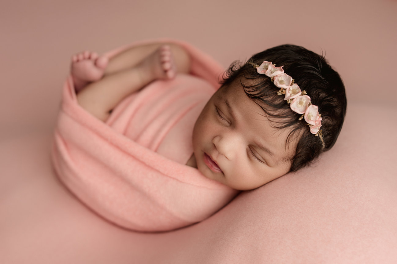 Cozy in-home newborn session with soft styling and wrapped poses