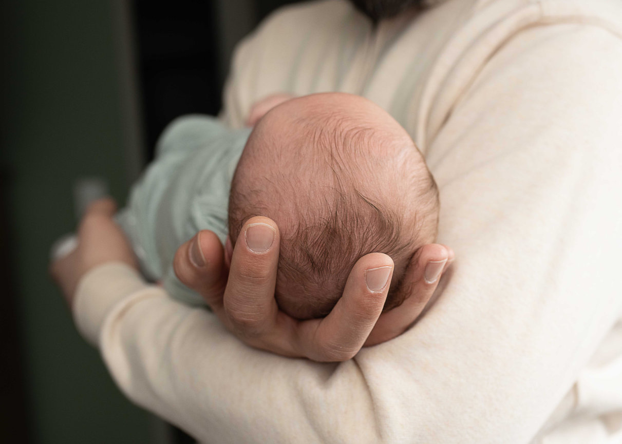 Adult cradling a newborn baby head in hands