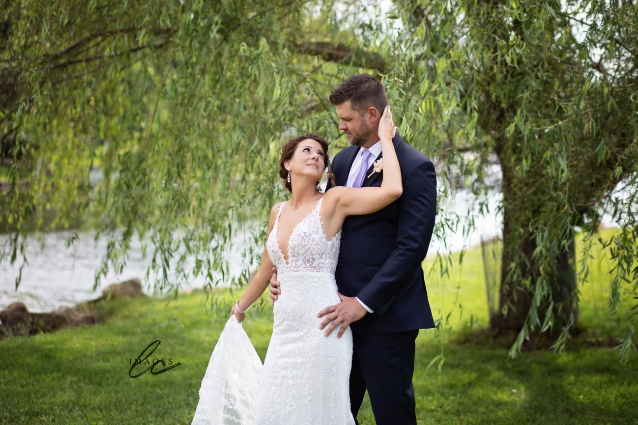 Bride and groom standing together under a willow tree