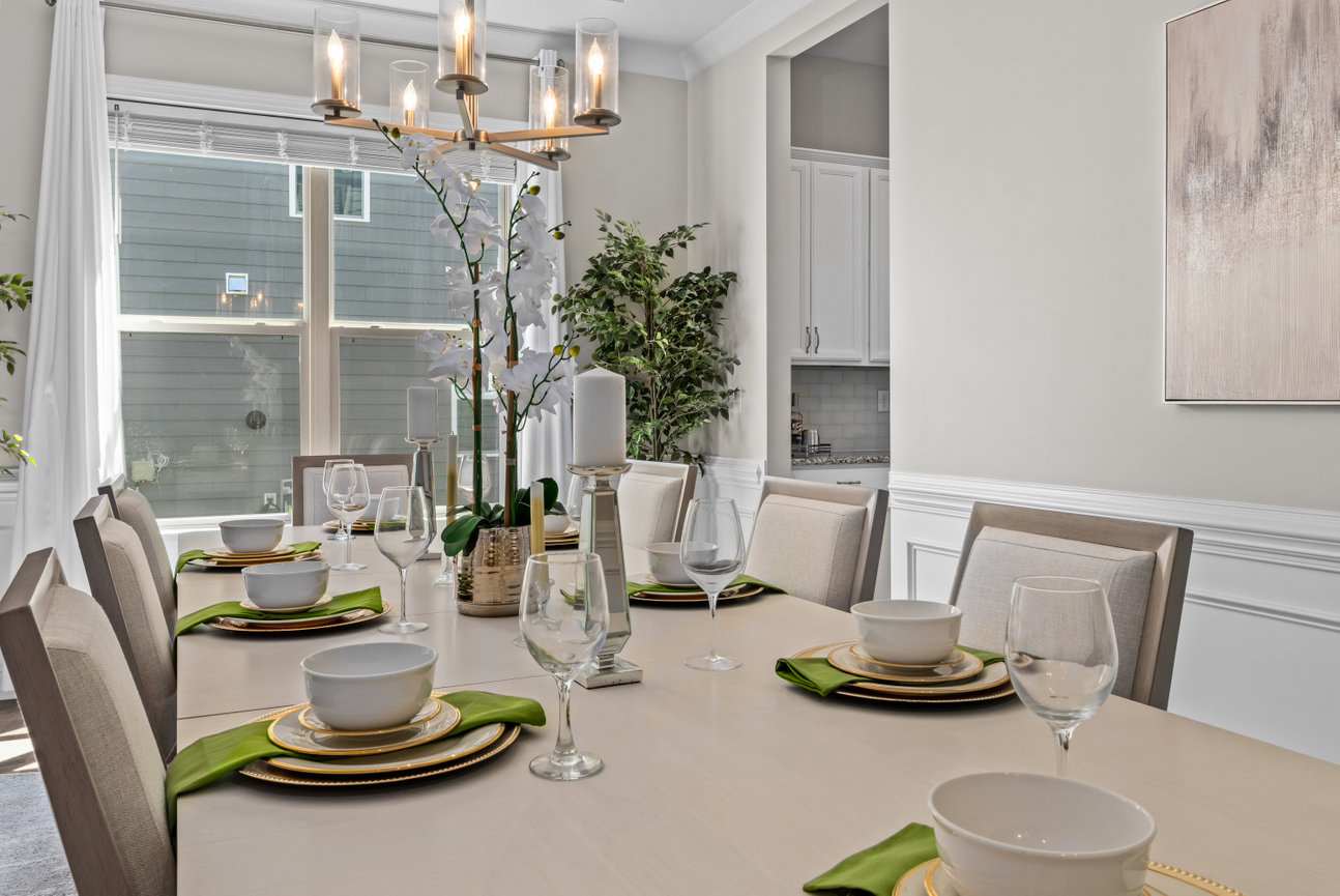 Elegant dining room with a set table, chandelier, large window, and floral centerpiece.