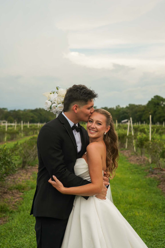 Bride and groom smiling together in a vineyard at golden hour.